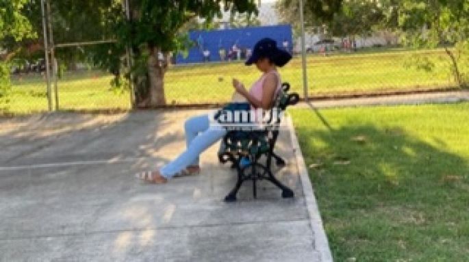 Una joven tejiendo en un parque, en vez de hablar por celular